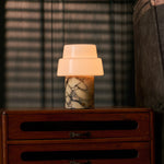 Pissarro Medium Calacatta Vionaro jaune lampe de table sans fil Tavellio – posée sur des livres, salon sombre – marbre doré veiné allumée