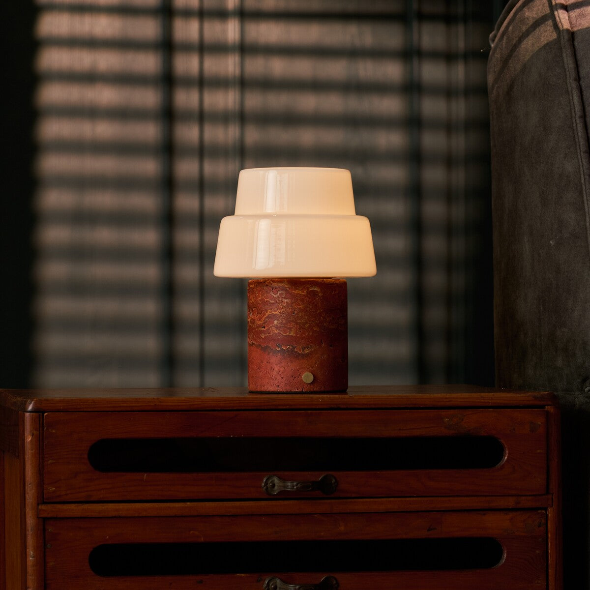 Cordless table lamp Pissarro Medium red travertine stone base with tiered white glass shade lit warmly