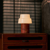 Cordless table lamp Pissarro Medium red travertine stone base with tiered white glass shade lit warmly