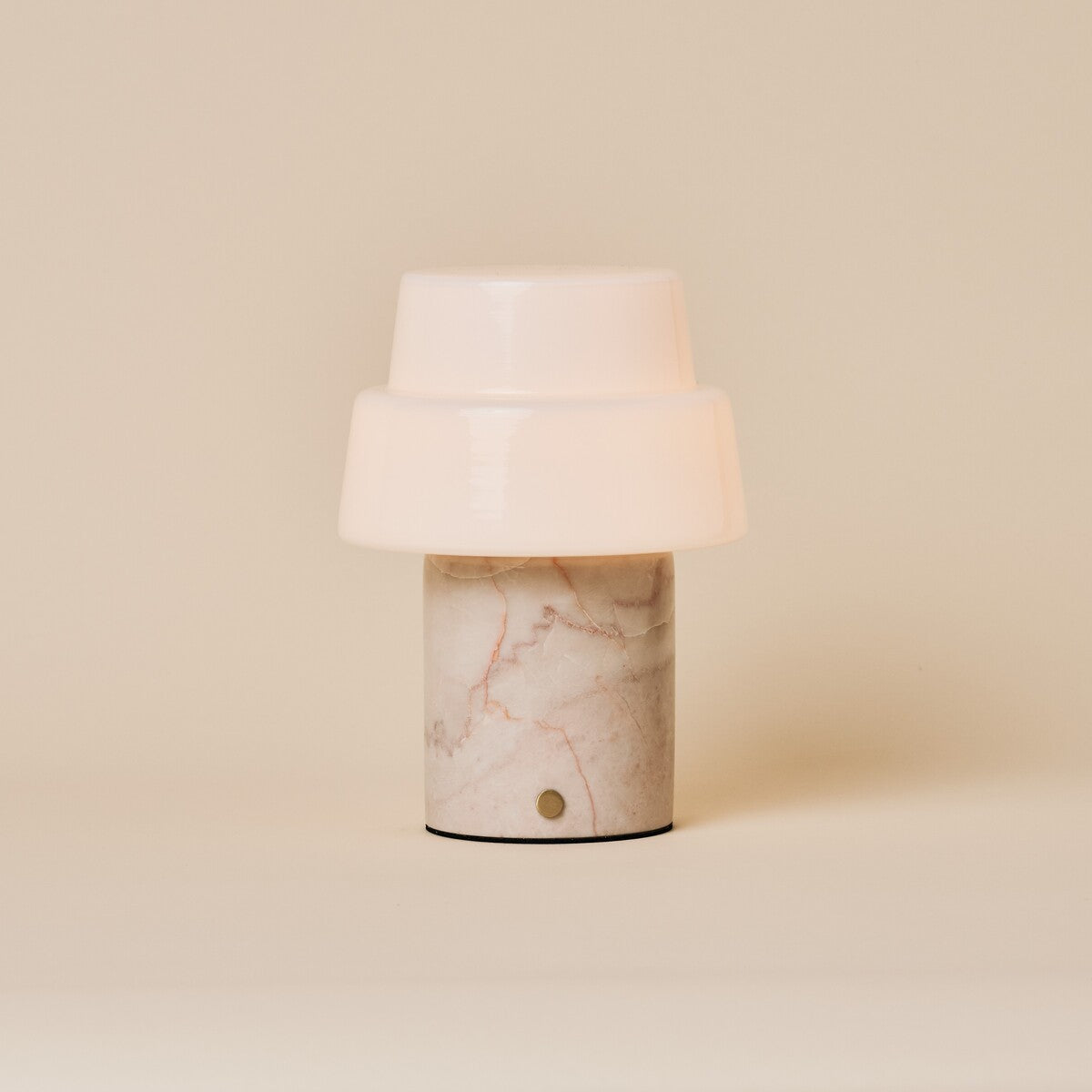 Rechargeable table lamp with opal glass dome shade and dark stone base on wooden sideboard