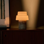 Pissarro cordless table lamp in silver travertine stone with warm glow on a wooden nightstand