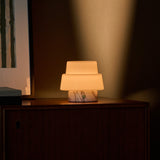 Oplaadbare tafellamp Pissarro Small Arabescato marmer met getrapte glazen kap op een houten dressoir