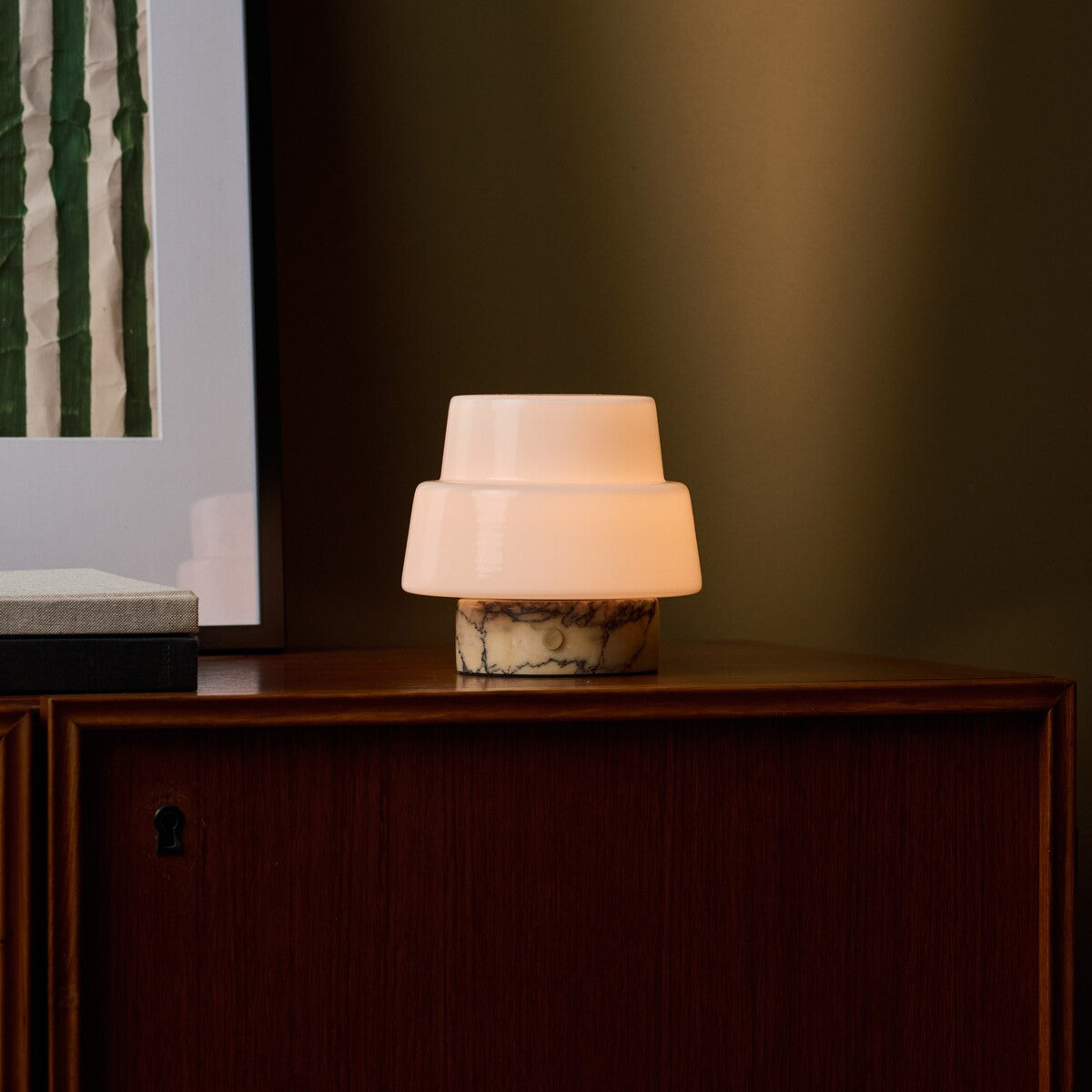Cordless table lamp Pissarro Small Calacatta Vionaro Yellow Marble glowing beside striped green art
