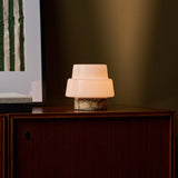 Cordless table lamp Pissarro Small Calacatta Vionaro Yellow Marble glowing beside striped green art