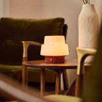 Oplaadbare tafellamp Pissarro Small rood travertin naast een groenfluwelen fauteuil