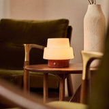 Oplaadbare tafellamp Pissarro Small rood travertin naast een groenfluwelen fauteuil