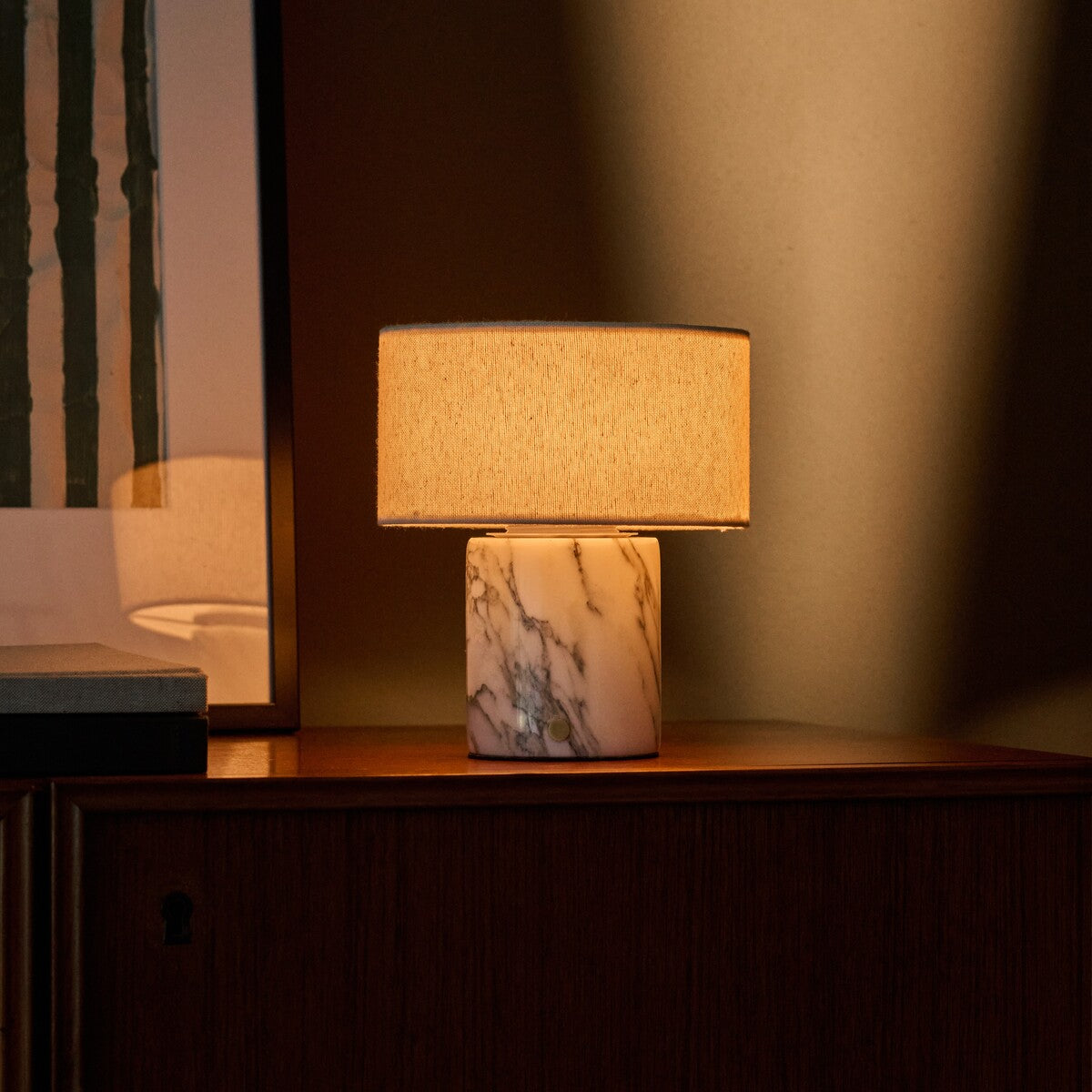Redon rechargeable table lamp with arabescato marble base illuminated on a dark wood sideboard