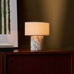 Redon cordless table lamp with arabescato white marble base beside framed art on a cabinet