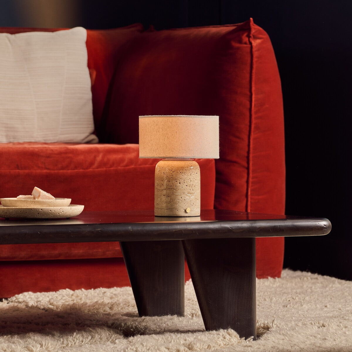 Redon cordless table lamp with beige travertine base and linen shade on dark coffee table