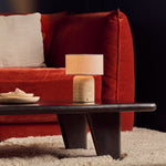 Redon cordless table lamp with beige travertine base and linen shade on dark coffee table