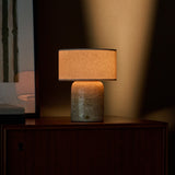 Redon Large cordless table lamp in beige travertine marble glowing on a wooden bedroom dresser