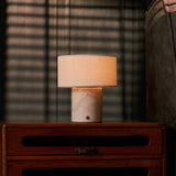 Redon rechargeable table lamp with rosa aurora marble base glowing on a bedroom nightstand