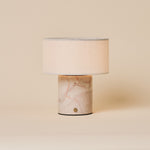 Redon cordless table lamp featuring a rosa aurora pink marble base and linen drum shade