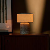 Redon cordless table lamp with silver travertine base and cream shade on wooden cabinet