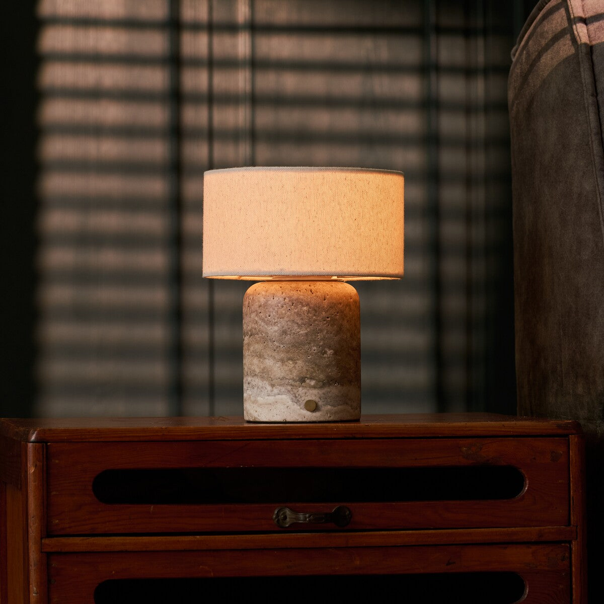 Redon rechargeable table lamp with silver travertine base glowing on wooden nightstand
