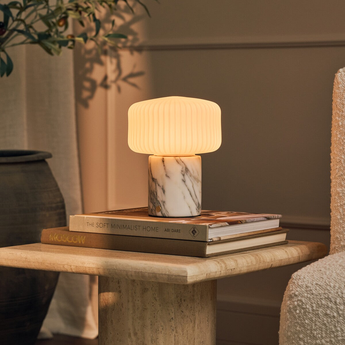 Renoir Medium cordless table lamp with arabescato marble base on a stack of interior books
