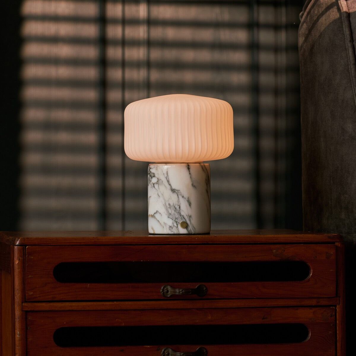 Renoir Medium cordless table lamp with arabescato marble base on a bedside wooden dresser