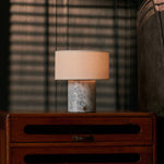 Rechargeable table lamp Redon with blue calcite marble base and ribbed opal glass shade on a red velvet sofa