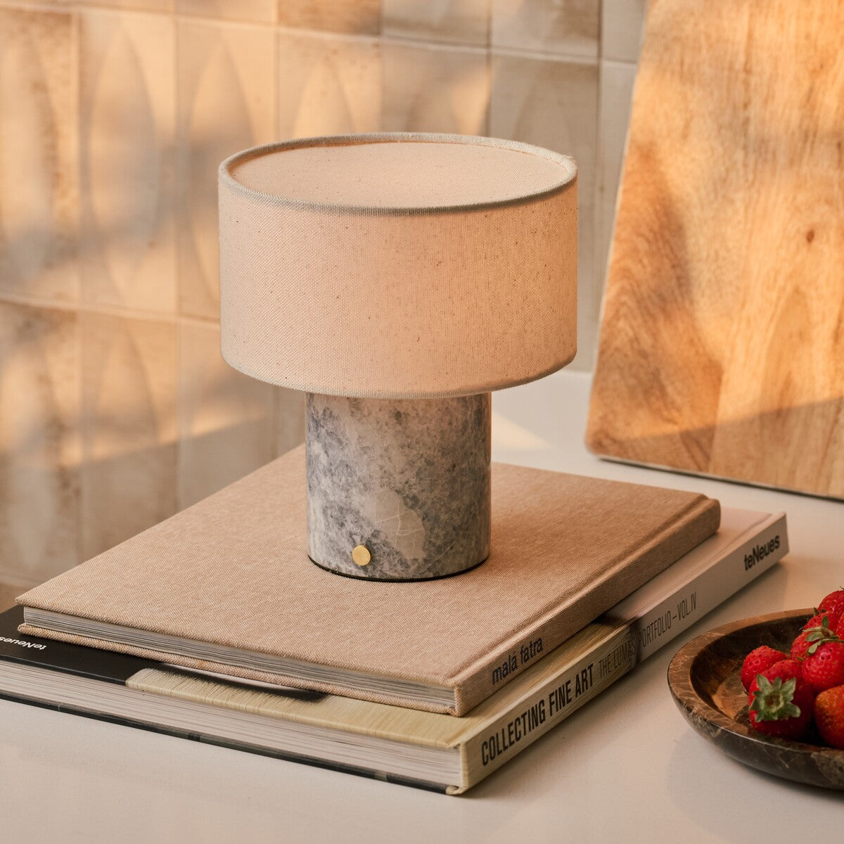 Cordless table lamp Redon with blue calcite marble base and ribbed opal glass shade on a marble side table