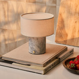 Cordless table lamp Redon with blue calcite marble base and ribbed opal glass shade on a marble side table