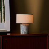 Rechargeable table lamp Redon with blue calcite marble base and ribbed opal glass shade beside a red sofa