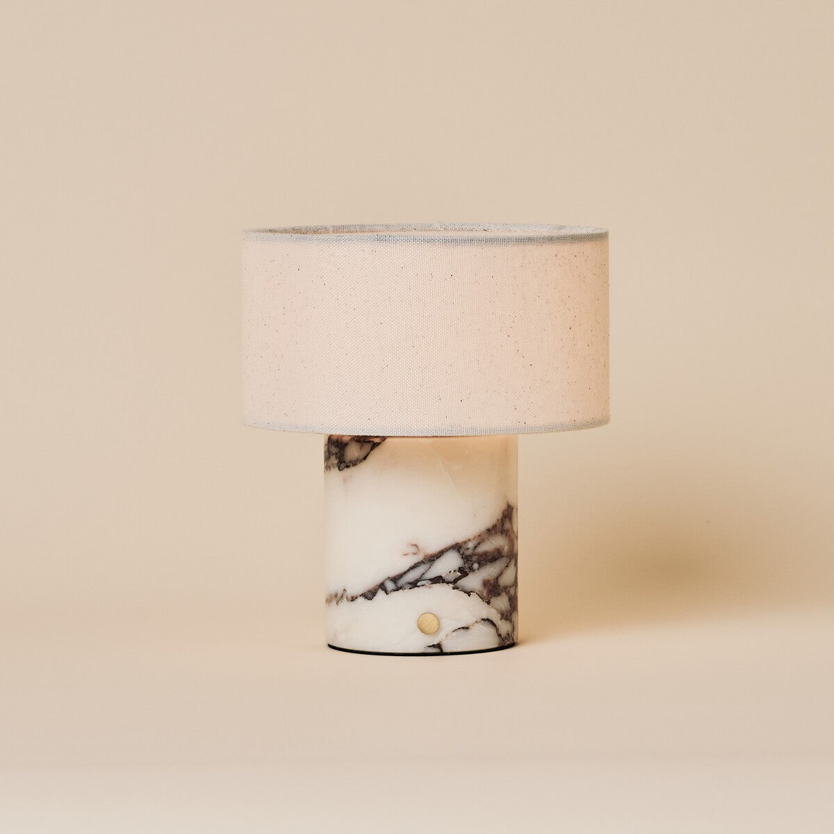 Cordless Redon table lamp in Calacatta white marble with a linen drum shade on a sideboard