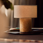 Cordless table lamp Redon with honey onyx marble base and ribbed opal glass shade on a stack of books
