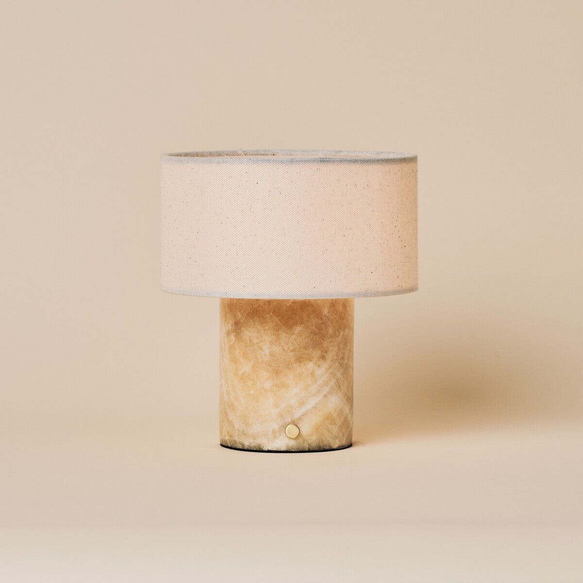 Redon cordless table lamp featuring an amber onyx marble base and beige linen drum shade