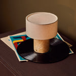 Rechargeable table lamp Redon with honey onyx marble base and ribbed opal glass shade beside a patterned cushion