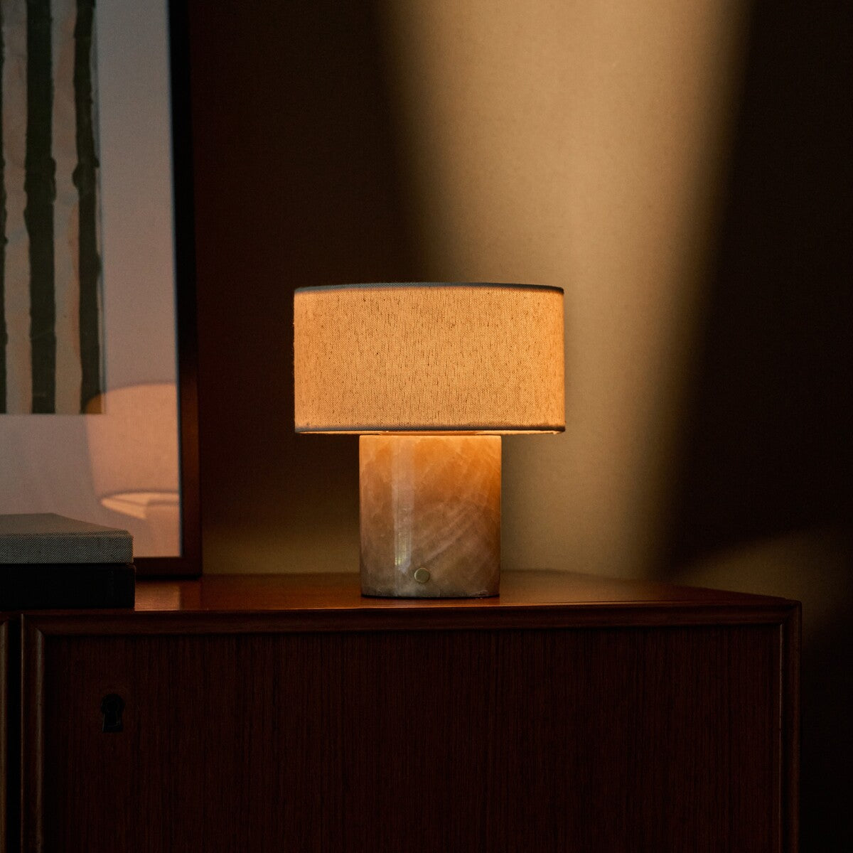 Redon cordless table lamp with amber onyx marble base illuminated on a dark wood sideboard