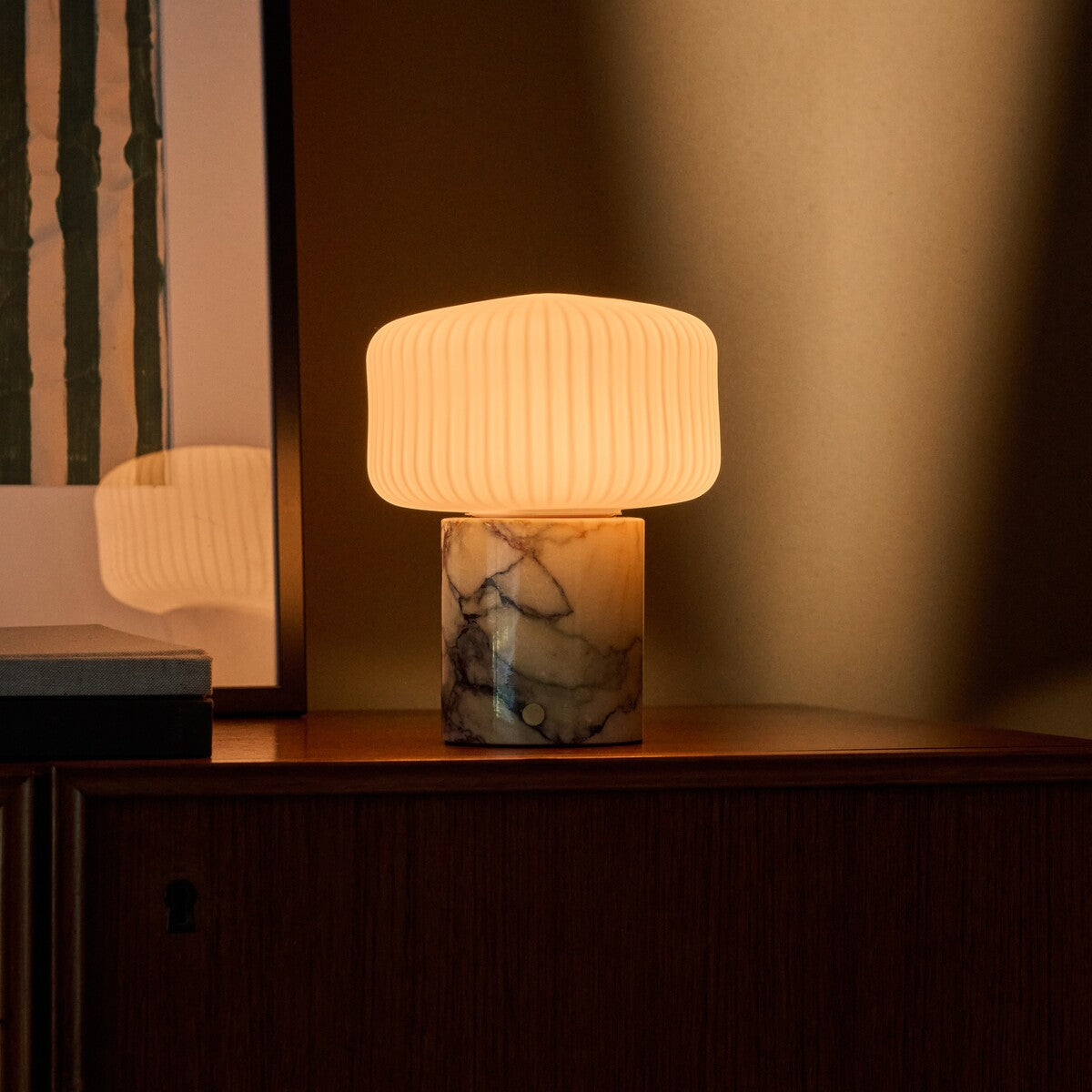 Rechargeable table lamp with Calacatta Vionaro yellow marble base lit beside a green velvet chair