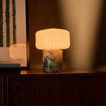 Rechargeable table lamp with Calacatta Vionaro yellow marble base lit beside a green velvet chair