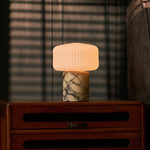 Cordless table lamp with Calacatta Vionaro yellow marble base glowing on a wooden bedside dresser