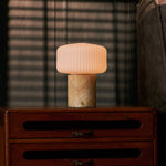 Renoir Medium rechargeable table lamp with honey onyx marble base on a wooden dresser