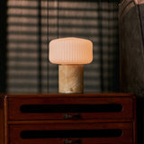 Renoir Medium rechargeable table lamp with honey onyx marble base on a wooden dresser