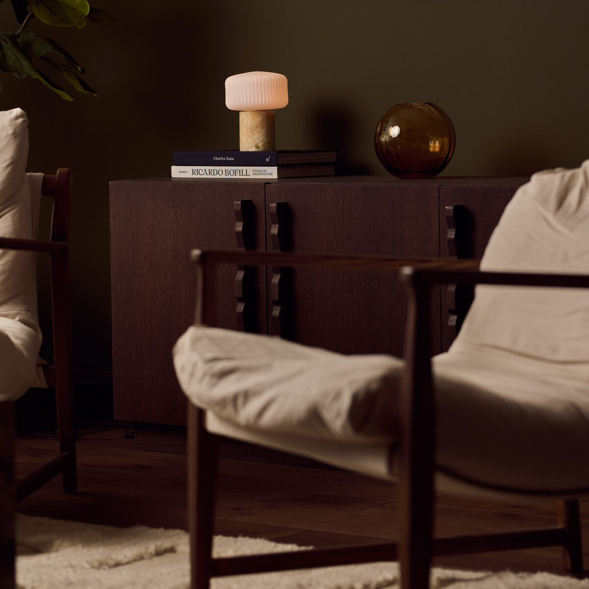 Renoir Medium cordless table lamp with honey onyx marble base glowing on a stacked side table