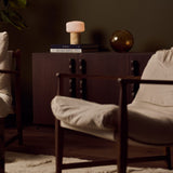 Renoir Medium cordless table lamp with honey onyx marble base glowing on a stacked side table