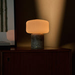 Rechargeable table lamp Renoir grey silver travertine base with ribbed glass shade on a wood cabinet
