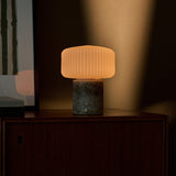 Rechargeable table lamp Renoir grey silver travertine base with ribbed glass shade on a wood cabinet