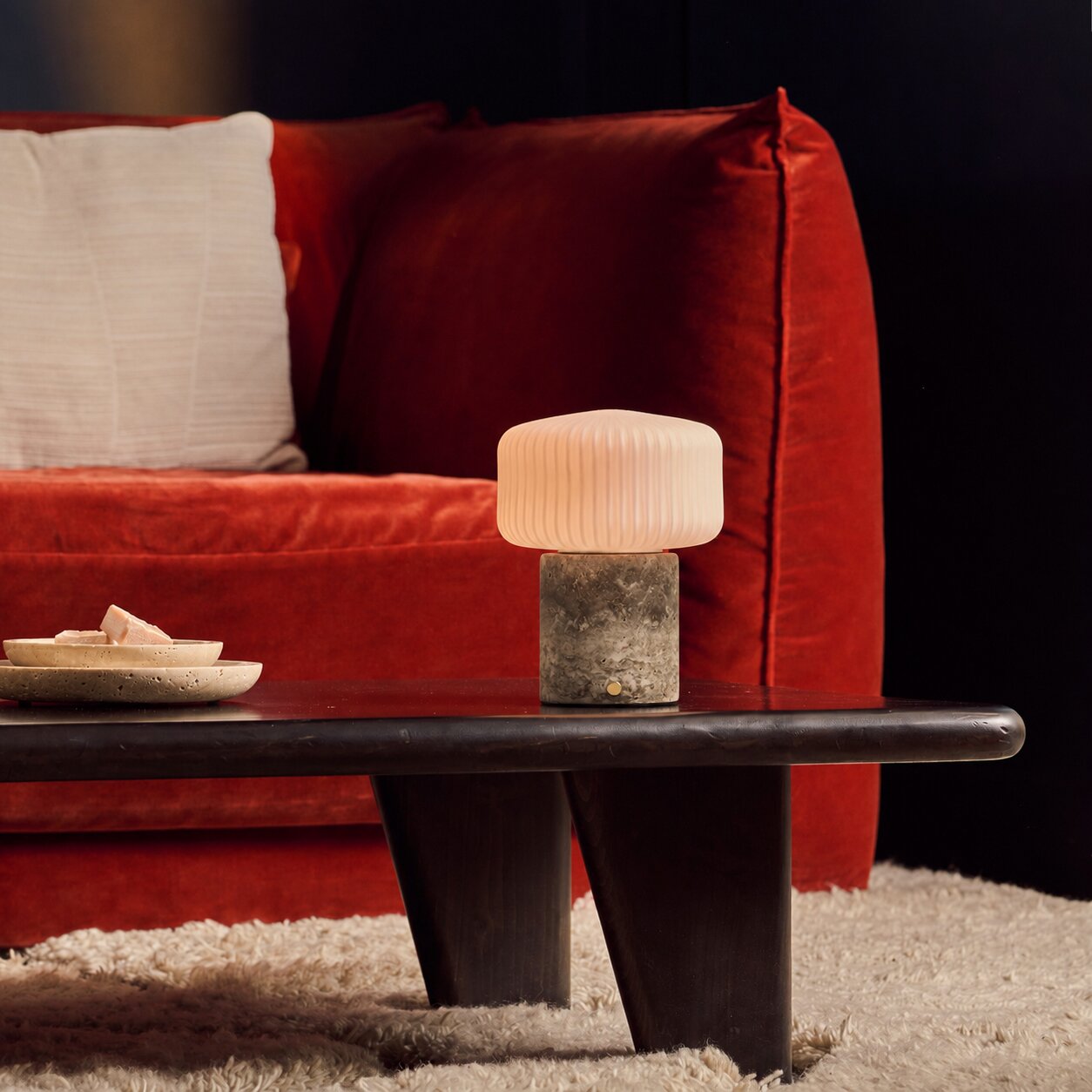 Cordless Renoir table lamp in silver travertine with a fluted glass shade on a stone block