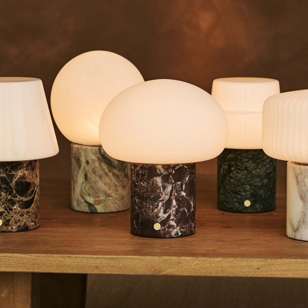 Tavellio Rijks Collection cordless table lamps in marble and travertine grouped on a wood table
