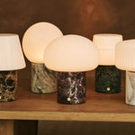 Tavellio Rijks Collection cordless table lamps in marble and travertine grouped on a wood table