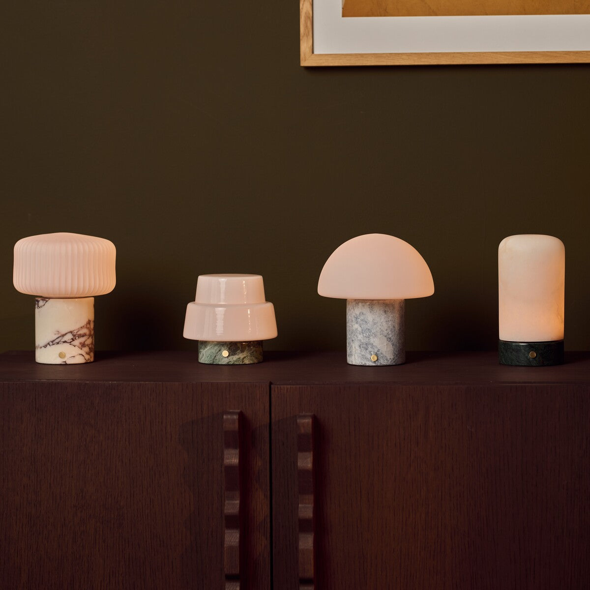 Tavellio marble table lamp collection including Blue Calcite, green, and Arabescato bases on a dark cabinet