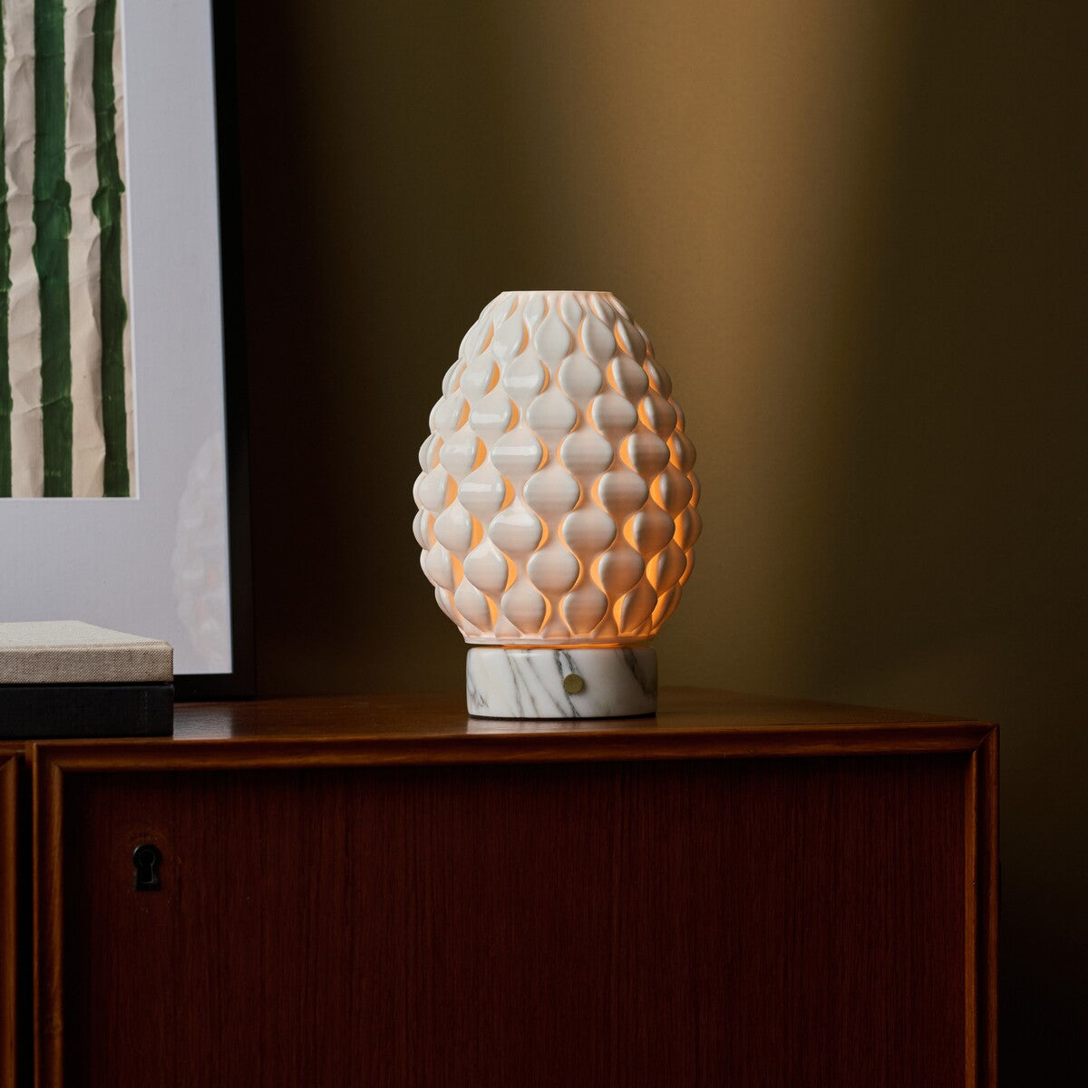 Cordless table lamp Serena Arabescato marble, cream porcelain shade glowing on wood sideboard