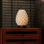 Cordless table lamp Serena Black wooden base, glowing porcelain shade on dark wood cabinet