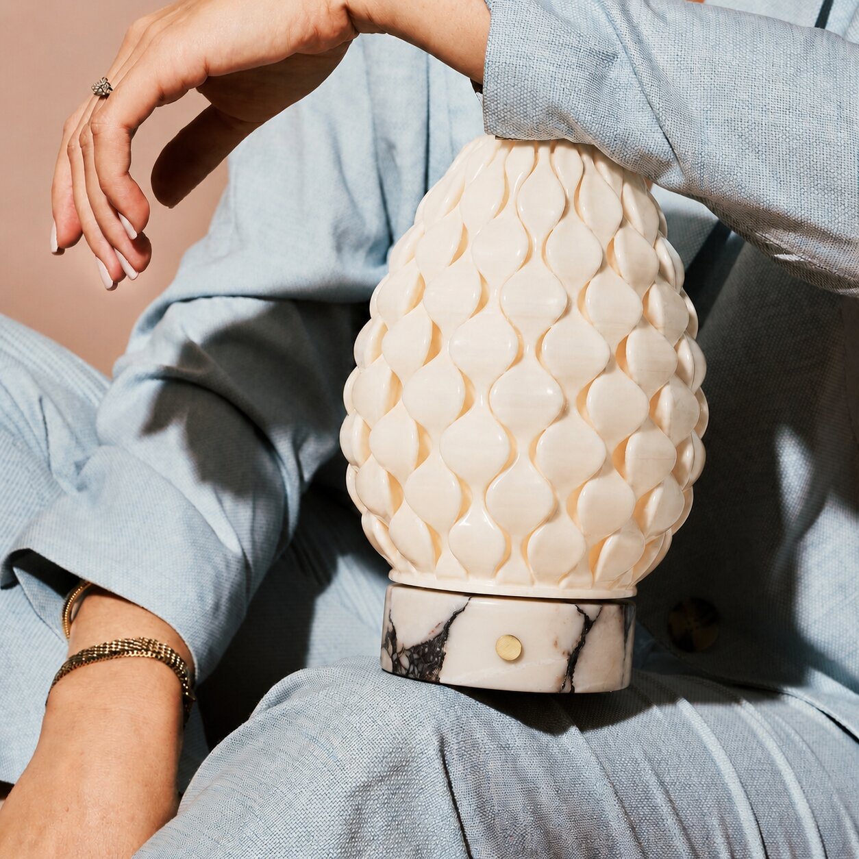 Serena cordless table lamp held close-up, white porcelain shade, white marble base detail