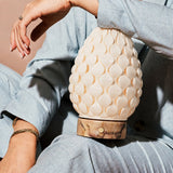 Serena cordless table lamp held close-up, white porcelain shade, pink marble base detail