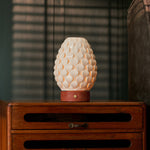 Rechargeable table lamp Serena red travertine porcelain shade glowing on wooden cabinet