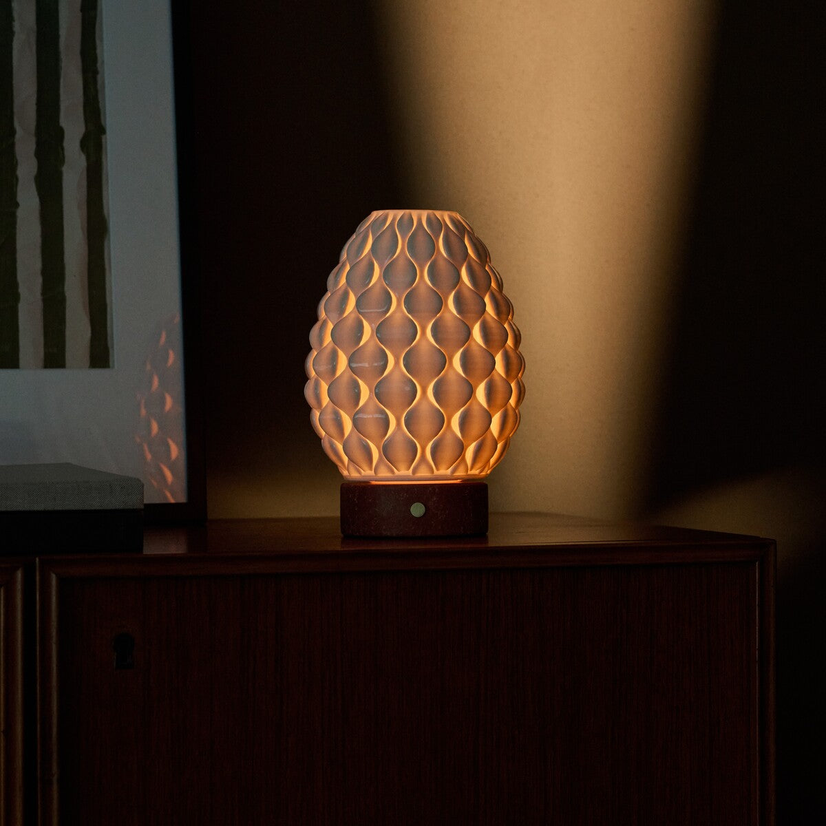 Cordless table lamp Serena red travertine porcelain shade beside framed green wall art
