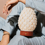 Rechargeable table lamp Serena red travertine porcelain shade held against blue clothing